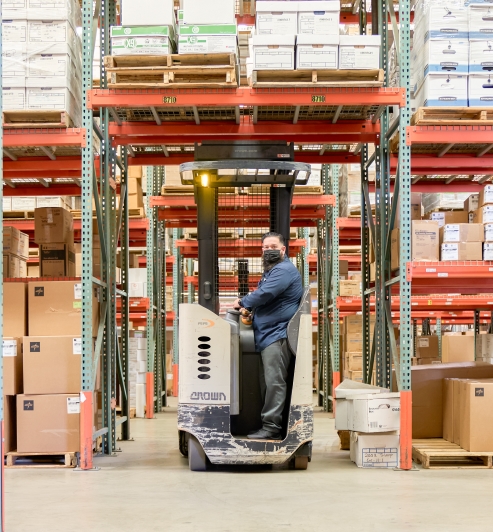 Roland Roman navigates the warehouse forklift to restock supplies.