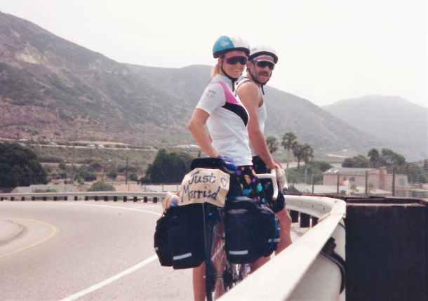 Lori and Tom O'Hern posing on their tandem bike during their journey from San Francisco to Manhattan Beach with a “Just Married” sign hanging from the back.