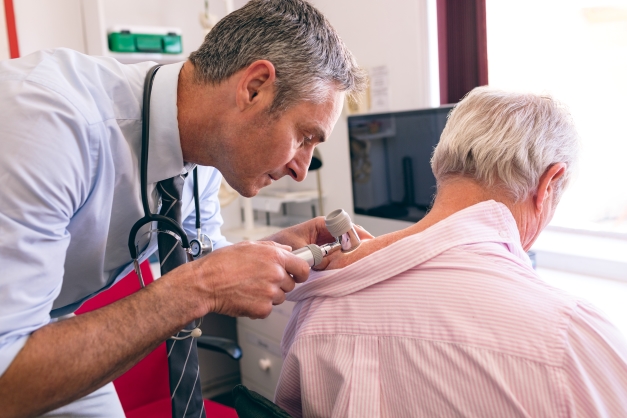 A dermatologist examines a patient's skin for possible cancers.